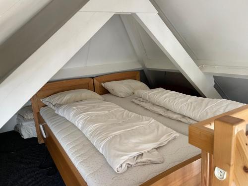 two unmade beds in a room with an attic at Erve Feenstra in Lochem