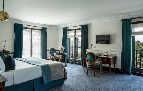 a hotel room with a bed and a desk and windows at Hôtel Brighton - Esprit de France in Paris