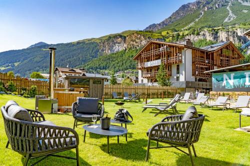 um grupo de cadeiras e mesas num quintal com uma casa em Nira Mountain Resort Futura em Valdidentro