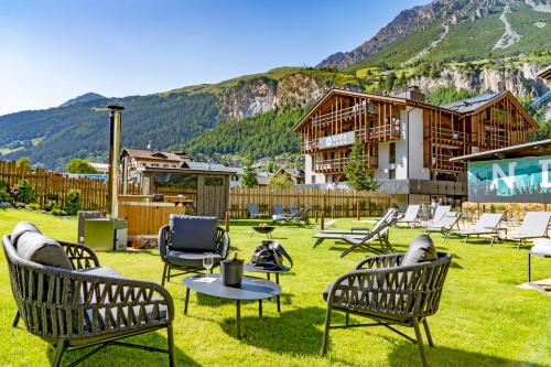 een groep stoelen en tafels in een tuin met een huis bij Nira Mountain Resort Futura in Valdidentro