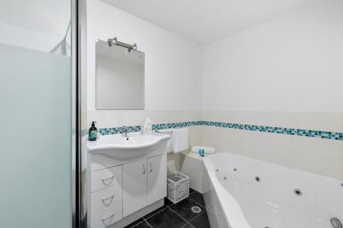 ein weißes Badezimmer mit einer Badewanne und einem Waschbecken in der Unterkunft Lorne Bush House Cottages & Eco Retreats in Lorne