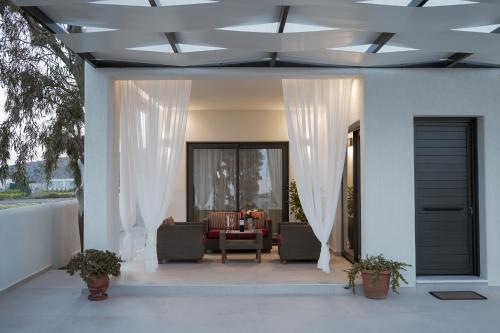 eine Veranda mit weißen Vorhängen und ein Wohnzimmer in der Unterkunft Villa Basilica Kalavria in Perivolos