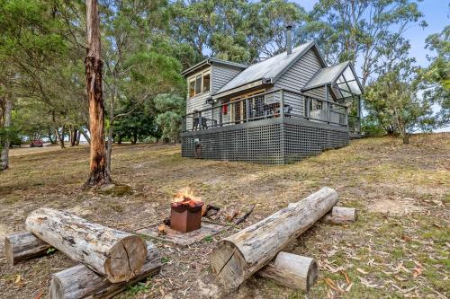 a house on a hill with a fire in front of it at Lorne Bush House Cottages & Eco Retreats in Lorne