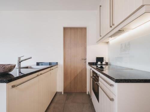 a kitchen with white cabinets and a sink at Village Park Suites by VAYA inklusive Zell am See Kaprun Sommer Karte in Zell am See