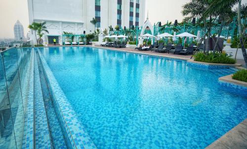 a large swimming pool with blue water in a building at Mekong River Jing Land Hotel in Jinghong