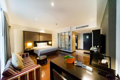a hotel room with a bed and a couch at Signature Pattaya in Pattaya South
