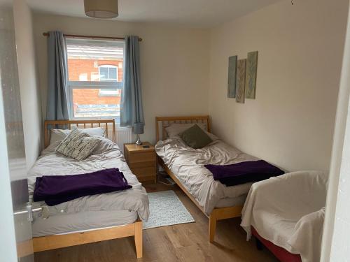 two twin beds in a room with a window at Spacious first floor apartment in the centre of Church Stretton with free parking in Church Stretton