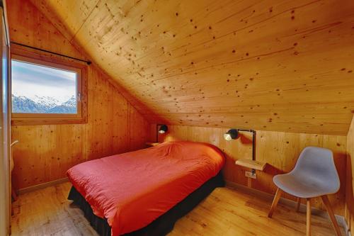 - une chambre dans une cabane en rondins avec un lit et une chaise dans l'établissement Chalet Gîte Magali de 2 à 12 pers, à Le Noyer