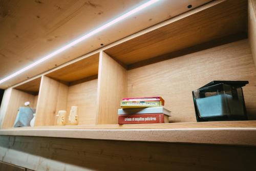 a shelf with books on it with a clock and books at Domaine Bohème I art de vivre in Guebwiller