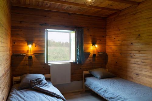 two beds in a wooden room with a window at la Bouinotte du Berry in Villegenon