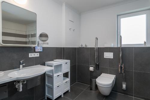 a bathroom with a sink and a toilet and a mirror at Westside Arthotel in Kühlungsborn