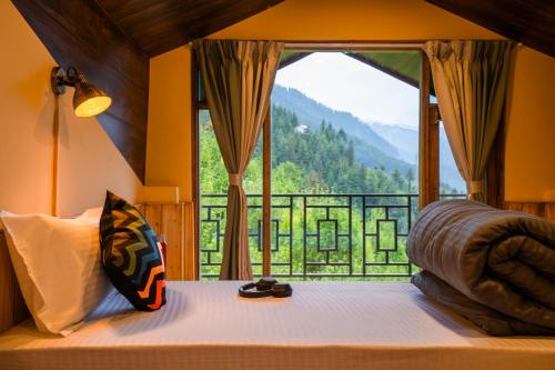 a bedroom with a bed and a large window at Zostel Manali, Vashisht in Vashisht