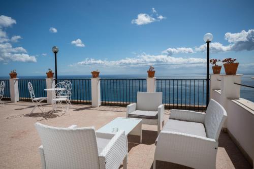 a balcony with chairs and tables and the ocean at Hotel Elios Tao in Taormina