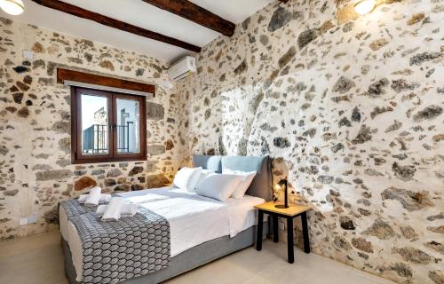 sypialnia z kamienną ścianą i łóżkiem w obiekcie Mirthia Apartments w mieście Plakias