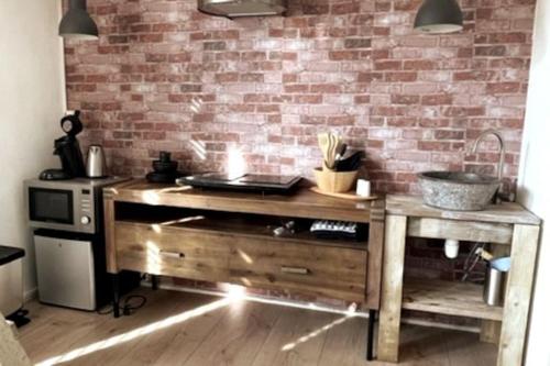 une cuisine avec un comptoir en bois et un mur en briques dans l'établissement Gezellige knusse studio met bubbelbad, à Huizen