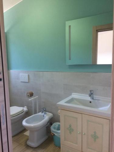 a bathroom with a sink and a toilet and a mirror at Villino nel Bosco in Capoliveri