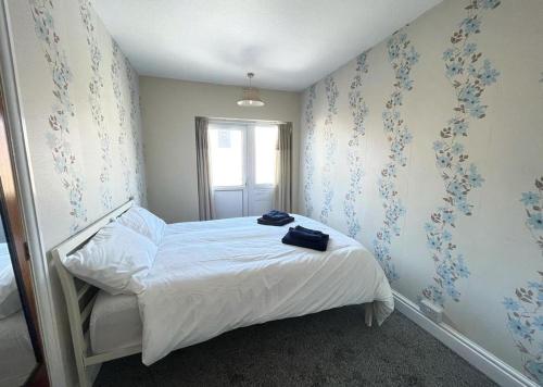 a bedroom with a bed with white sheets and blue wallpaper at 1 Bedroom Holiday Apartment Skegness - Flat 14 in Skegness