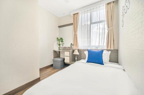 a white bedroom with a blue pillow on a bed at MEADOW by Kozystay - MACAN Museum in Jakarta