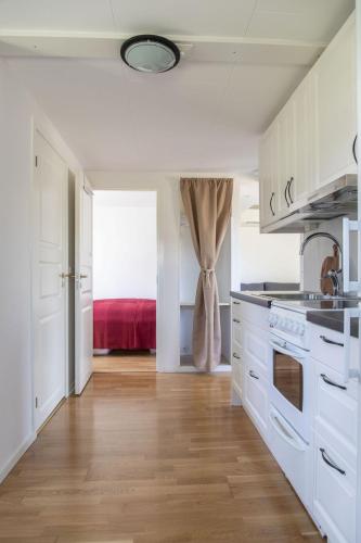 a kitchen with white cabinets and a red bed at Lilla Paradiset in Tomelilla