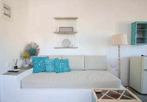 a white living room with a white couch and blue pillows at Enea by TinosHost in Tinos Town