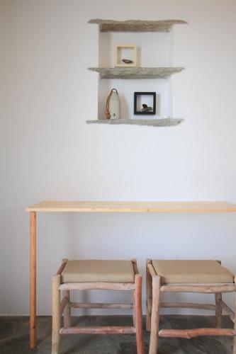 a table and two stools in a room at Enea by TinosHost in Tinos Town