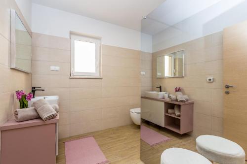 a bathroom with a sink and a toilet and a mirror at Villa QUERCUS in Krk