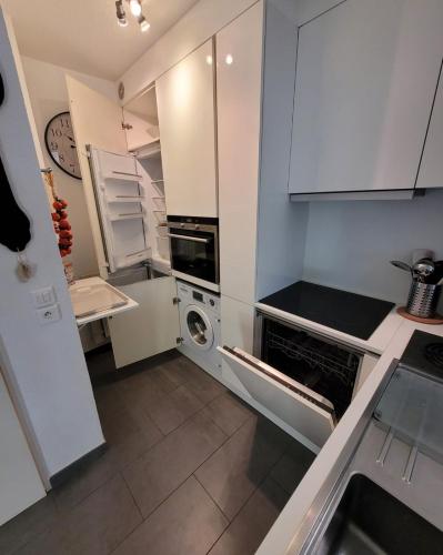 une cuisine avec des armoires blanches et une laveuse et une sécheuse dans l'établissement O logis du Port, à Argelès-sur-Mer