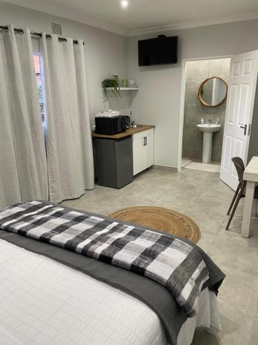 a bedroom with a bed and a bathroom with a sink at 10 Paul Roos in Kimberley