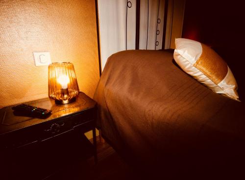 a bedroom with a bed and a lamp on a night stand at Résidence LE11B in Uzerche