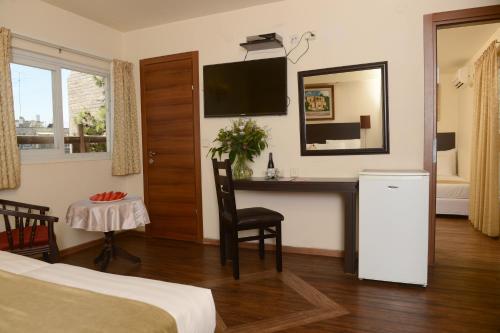 a hotel room with a bedroom with a desk and a television at A Little House In Rechavia in Jerusalem