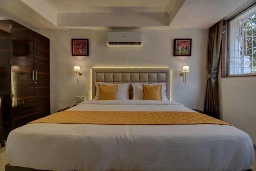 a bedroom with a large white bed with orange pillows at Elite Hotel in Lonavala