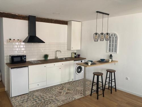 una cocina con armarios blancos y una barra con taburetes en La Casita del Río - Riverside Home en Cuenca