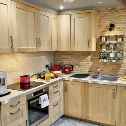 une cuisine avec des armoires en bois et un évier dans l'établissement In Sarlat Luxury Rentals, Medieval Center - Loft Stella Matutina -2p-ascenseur-climatisation, à Sarlat-la-Canéda