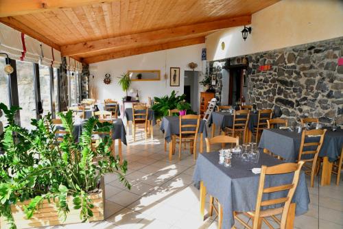 un restaurant avec des tables et des chaises et un mur de pierre dans l'établissement Logis Hôtel-restaurant La Mère Biquette, à Saint-Pons