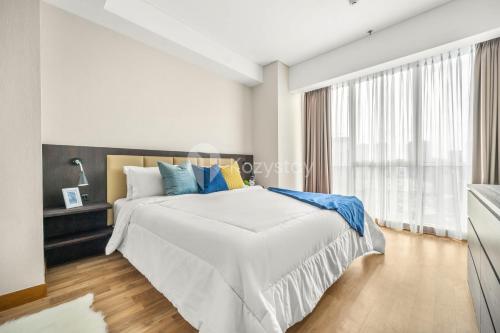 a white bedroom with a large bed and a window at LONDON by Kozystay - Kuningan in Jakarta