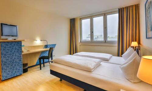 a hotel room with a bed and a desk with a computer at Hotel Le Village in Winnenden