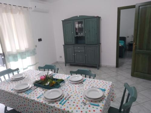 una mesa de comedor con platos y flores. en MaRo Apartment, en Cala Liberotto