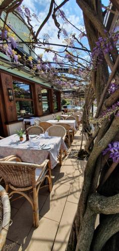 a patio with tables and chairs and a tree with purple flowers at Hotel Schön in Aßmannshausen