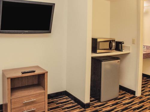a room with a tv and a refrigerator and a microwave at Quality Suites Lake Wright - Norfolk Airport in Norfolk