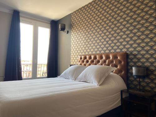 a bedroom with a large bed with white pillows and a window at Hotel Regina in Sète