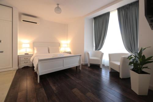 a white bedroom with a bed and two chairs at Perla Sudului - Residence in Timişoara