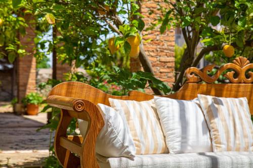 a wooden bench with white pillows on a patio at Samos Wine Factory Guesthouse Villa in Karlovasi