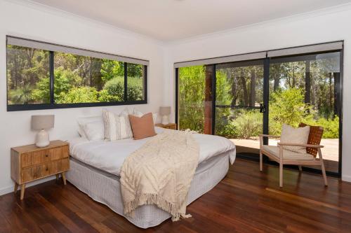 a bedroom with a large bed and large windows at Twilight Ridge - Situated on 2 acres of pristine bushland, Twilight Ridge offers both privacy and space in Quindalup