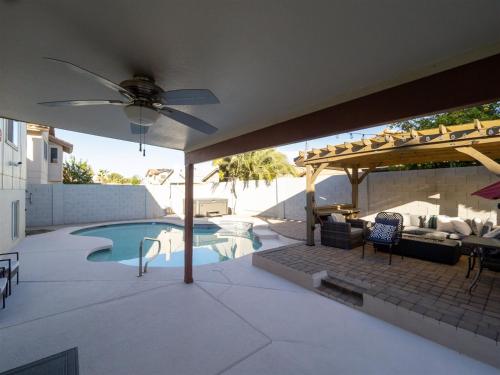 un patio con sombrilla y piscina en Spacious house with pool heater, hot tub, billiards, en Phoenix
