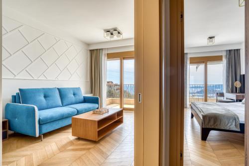a living room with a blue couch and a bed at Quercus Residences Apartments in Sveti Stefan