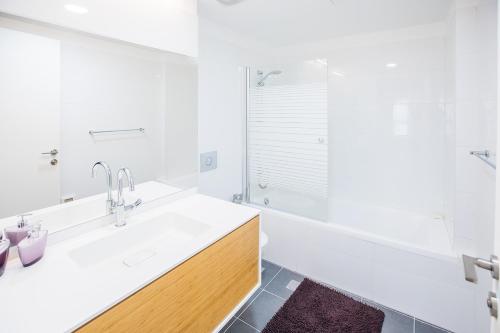 a white bathroom with a sink and a tub at The Haneviim Court - 3BDR High Standard in Jerusalem