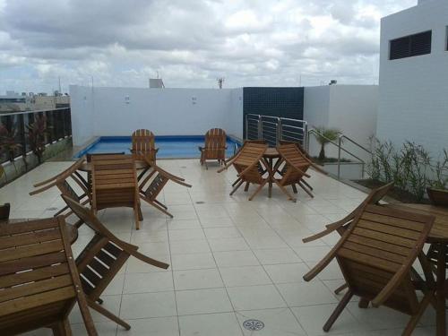 a patio with wooden chairs and a table on a roof at Moderno apartamento perto da praia in Maceió