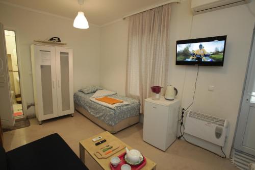 Habitación pequeña con cama y TV en la pared. en Sukhum City Mini Hotel en Sukhum