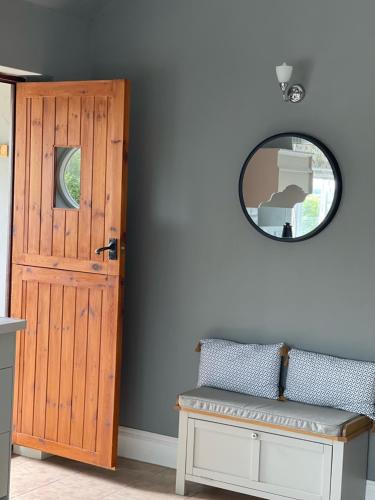 a room with a door and a mirror and a bench at Oxley Cottage in Alford