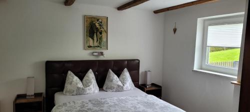 ein Schlafzimmer mit einem Bett mit Kissen und einem Fenster in der Unterkunft Ferienwohnung Lohnerlehen in Marktschellenberg